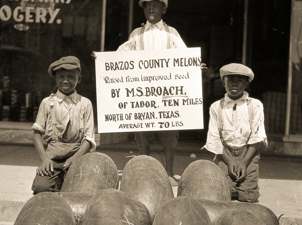 Three African American children selling watermelons in Downtown Bryan.