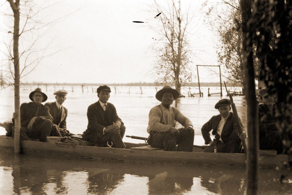 men in boat during flooding.
